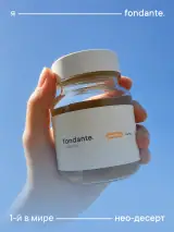 Стеклянная банка овсяной пасты Fondante Синабон в руке на фоне неба